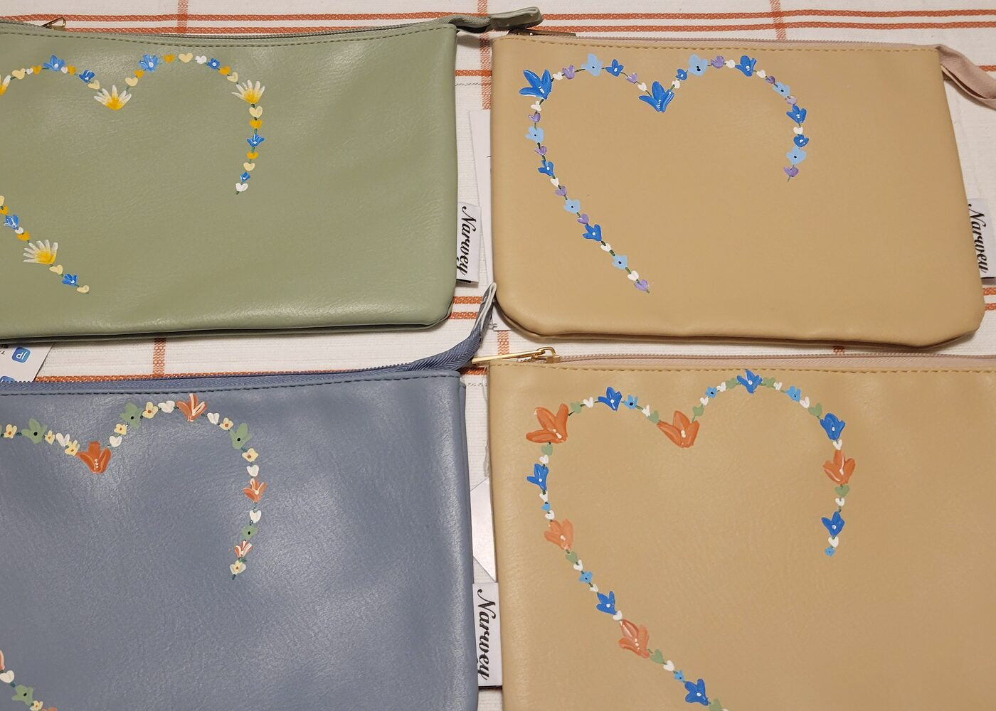 Four leather zip pouches painted with hearts made of small flowers